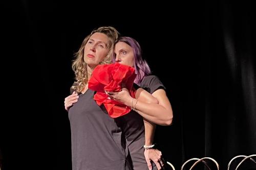 Two actresses on stage stand close to each other.