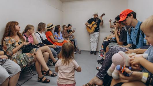 Teenagers, parents, and facilitators continue a music session in an air raid shelter during the Kid Friendly Summer Lab in Odesa, Ukraine.