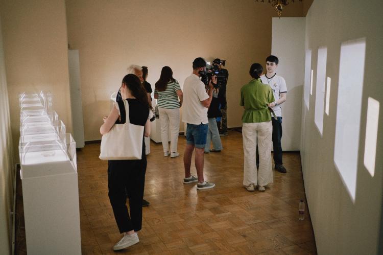 Besucher*innen stehen vor W&auml;ndern und Tischen mit Ausstellungsst&uuml;cken.