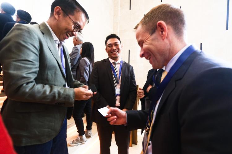 Participants exchance business cards outside plenary