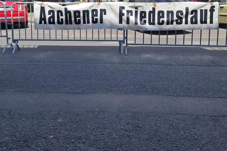 Schild mit Schriftzug "Aachener Friedenslauf" auf der Strecke