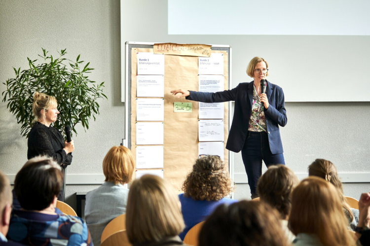 Eine Partnerin von Pro Peace steht auf der B&uuml;hne und erl&auml;utert das Konzept unseres Inlandsprogramms