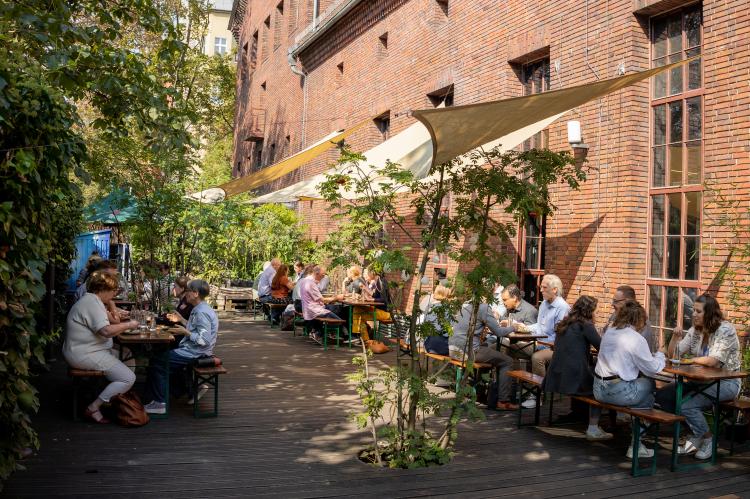 Im Innenhof des Veranstaltungsortes sitzen Menschen auf Bierbänken.