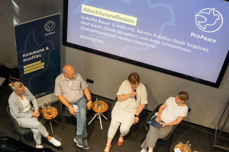 Teilnehmende einer Podiumsdiskussion aus der Vogelperspektive.