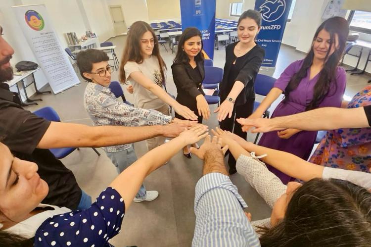 Irak: Teilnehmende eines Workshops legen ihre H&auml;nde aufeinander