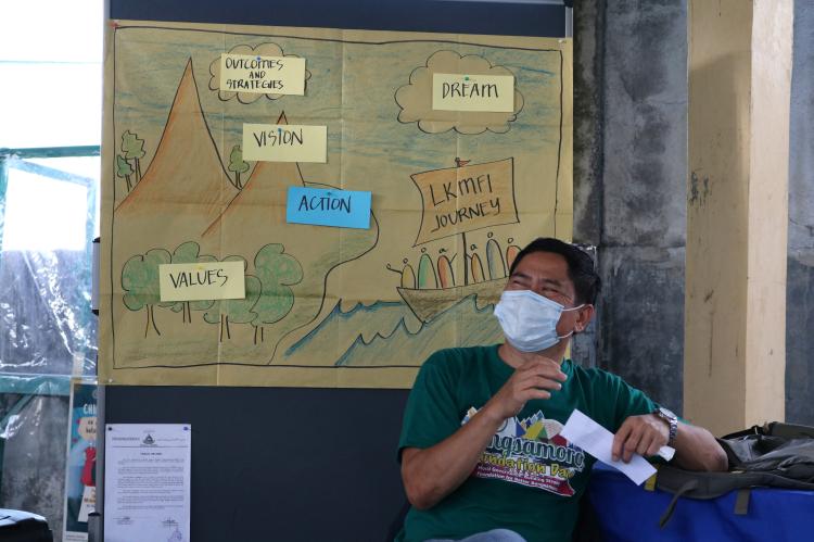 Salem Demuna in front of a pinboard with LKMFI's vision.