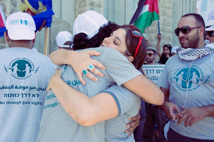 Zwei Aktivist*innen umarmen sich. Im Hintergrund sind gl&uuml;ckliche Menschen zu sehen.