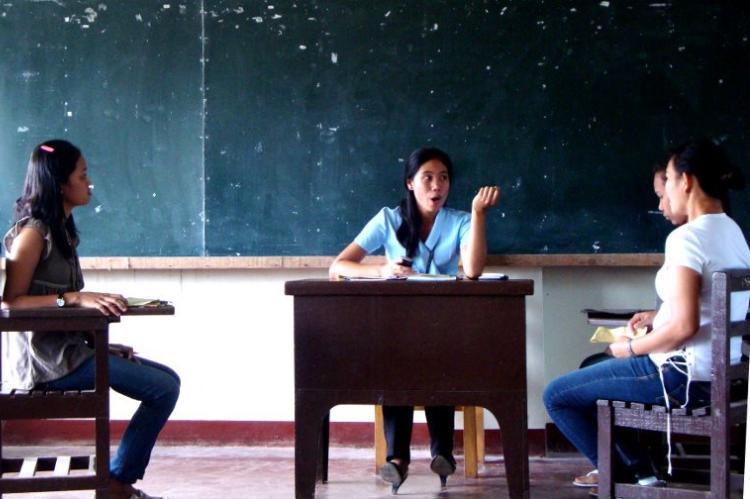Drei Studierende unterhalten sich in einem Klassenzimmer auf den Philippinen