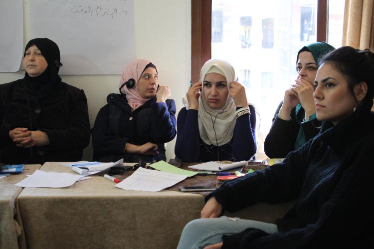 Five women sitting around a desk, listening to a speaker not visible in the picture