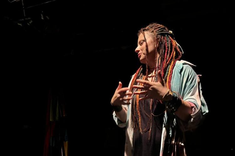 An actress with colourful hair performes on stage.