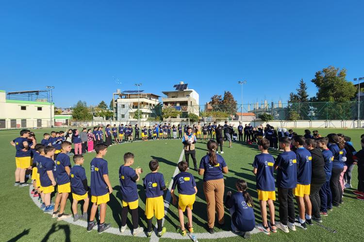 Viele Jugendliche in Fußballtrikots stehen im Mittelkreis eines Fußballfelds.