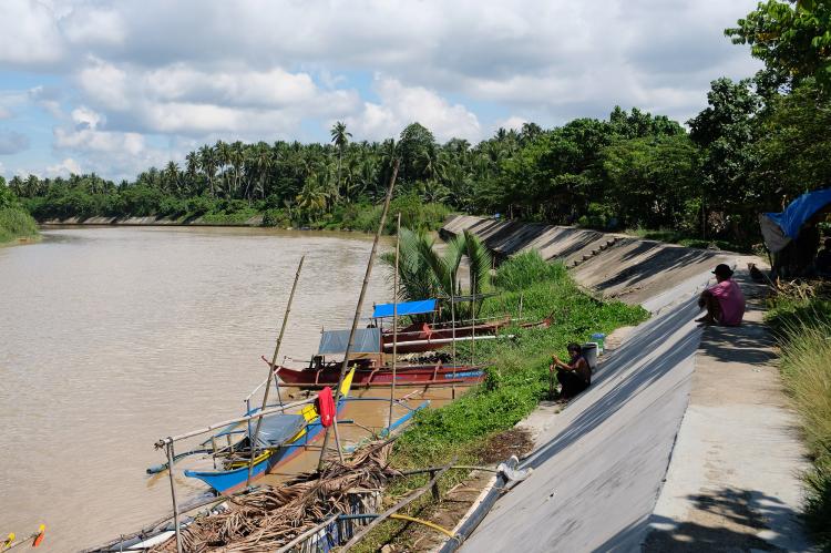 Villagers sitting on the riverbed next to their boats on the Hijo river