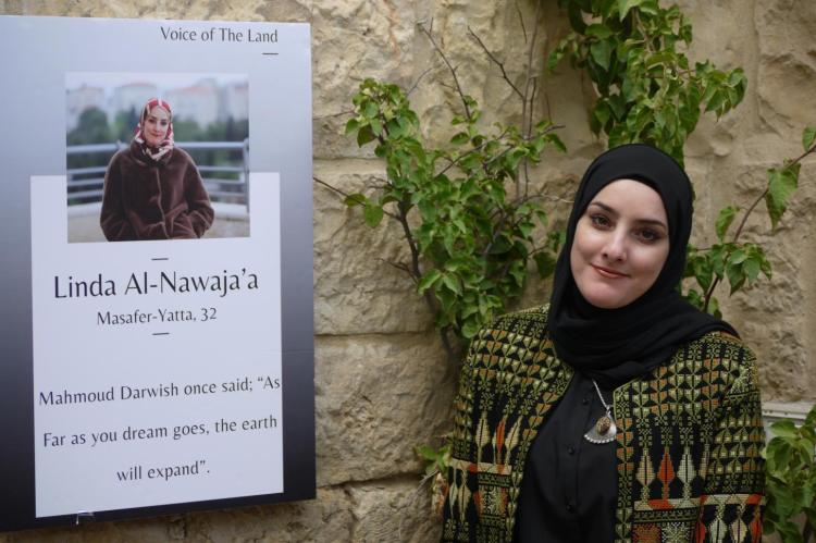 Young artist Linda standing next to a portrait and an information board about her.