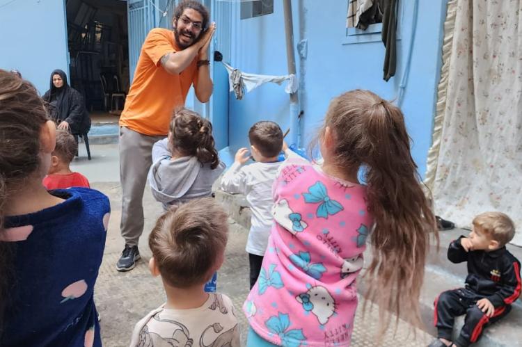 A man plays with a group of children.
