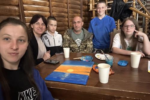 A veteran and family members pose with their completed artwork during a family art workshop at the Point of Support rehabilitation retreat in Chernivtsi Oblast, Ukraine.
