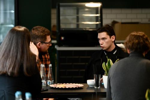 Vier junge K&uuml;nstler*innen f&uuml;hren eine Konversation.