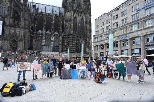 Eine Gruppe von Menschen h&auml;lt Kopft&uuml;cher in die H&ouml;he, um an den Genozid von Srebrenica zu erinnern.