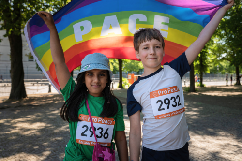 Kinder halten Pace-Flagge beim Friedenslauf von Pro Peace
