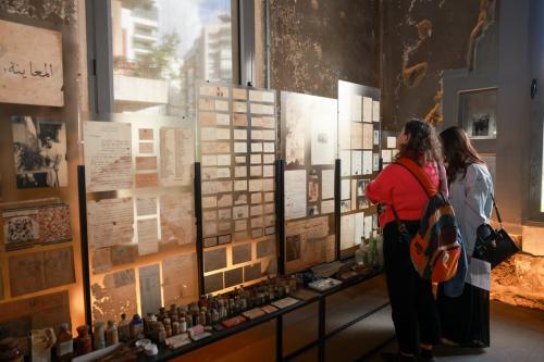 Two visitors look at exhibits from the Hkeeli exhibition, which are attached to a glass wall.