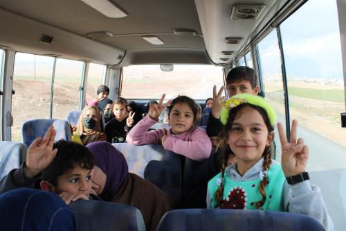 Kinder sitzen im Salam-Bus und l&auml;cheln freudig in die Kamera.