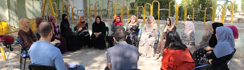 Iraq_Women participants sitting in a circle on chairs in a playground