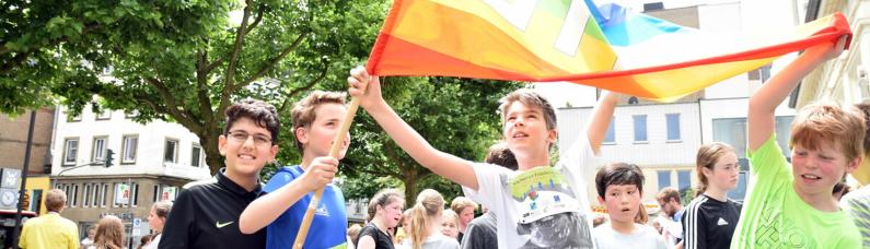 Jugendliche halten bei einem Friedenslauf von Pro Peace eine PACE-Flagge hoch