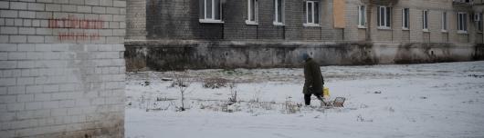 Eine Person l&auml;uft vor einem Haus in der Ukraine im Schnee.