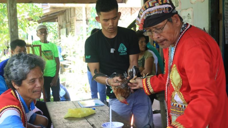 Indigenous youth assist their traditional leader in a ritual