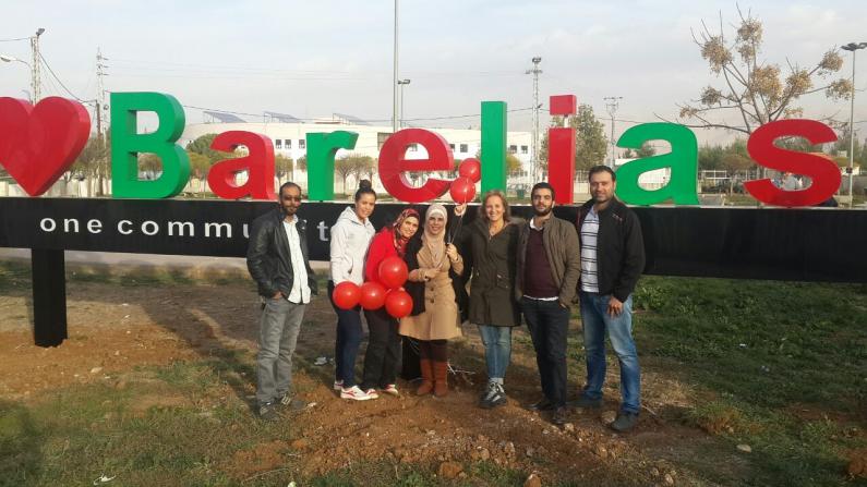 Projektpartnerinnen des forumZFD und Bewohner der Stadt Barelias vor dem Schriftzug „We love Barelias"