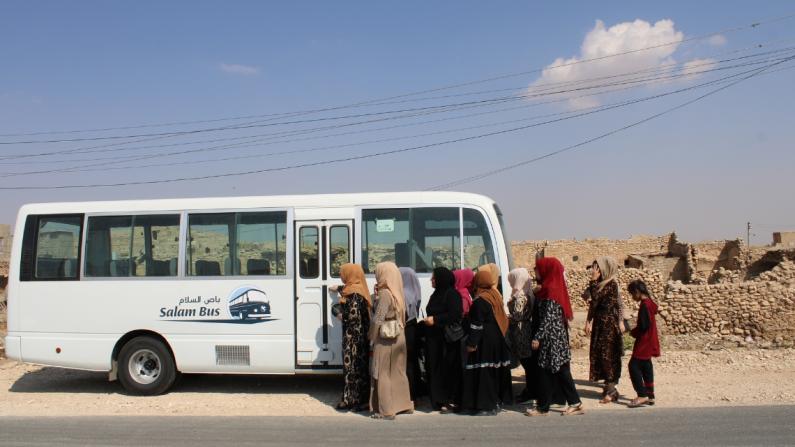 Frauen steigen in den Salam-Bus, der vor zuerstörten Häusern steht. Frauen steigen in den Salam-Bus, der vor zuerstörten Häusern steht.