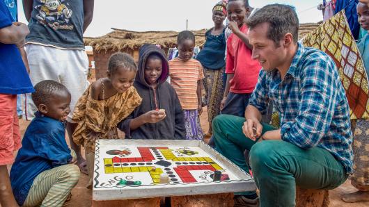 Bild aus dem Welterforscher Film: Willi Weitzel spielt ein Brettspiel mit Kindern 