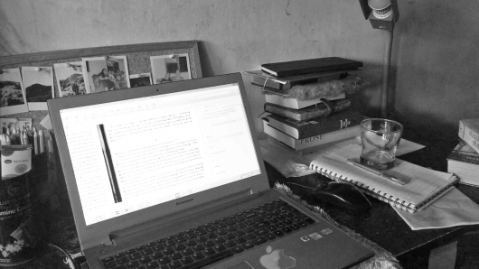 A teacher's home office desk filled with laptop and documents