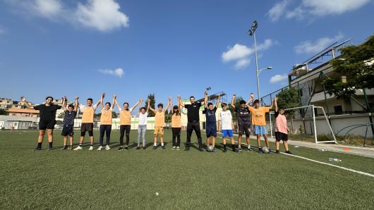 Coach with kids in field raising hands up