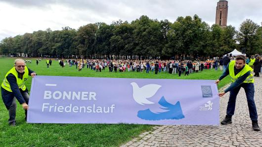 Helfer halten Banner zum 17. Bonner Friedenslauf