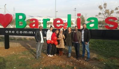 Projektpartnerinnen des forumZFD und Bewohner der Stadt Barelias vor dem Schriftzug „We love Barelias"