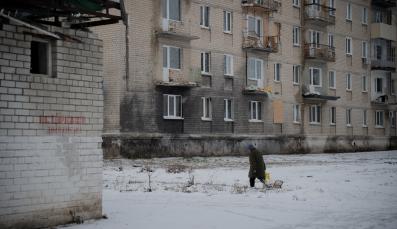 Eine Person l&auml;uft vor einem Haus in der Ukraine im Schnee.