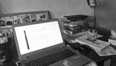 A teacher's home office desk filled with laptop and documents
