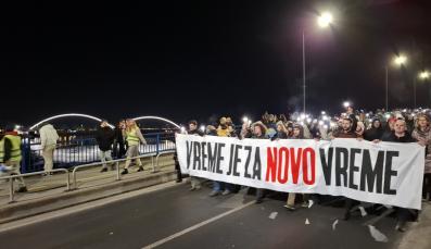 Ein Demonstrationszug zieht einen Banner tragend über eine Brücke.