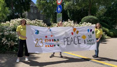 Helfer*innen halten das Startbanner des 23. Aachener Friedenslaufes