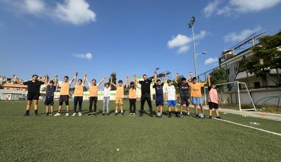 Coach with kids in field raising hands up