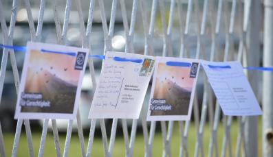 Postkarten, adressiert an die Mütter von Srebrenica, hängen aufgereiht an einem Zaun.