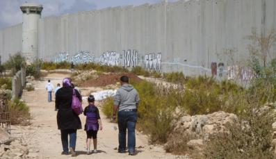 Eine Gruppe von Menschen läuft entlang ener Grenzmauer in Israel