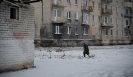 Eine Person l&auml;uft vor einem Haus in der Ukraine im Schnee.