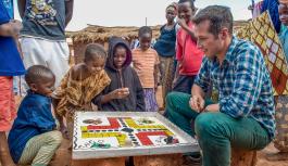 Bild aus dem Welterforscher Film: Willi Weitzel spielt ein Brettspiel mit Kindern 