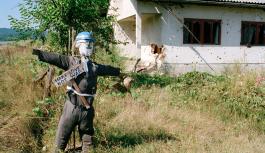 Eine Vogelscheuche, die als Peace Keeper der Vereinten Nationen verkleidet ist, vor einem Haus mit Einschussl&ouml;chern in der Stadt Kostajnica an der Grenze zu Kroatien in Nordbosnien.