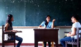 Drei Studierende unterhalten sich in einem Klassenzimmer auf den Philippinen