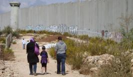 Eine Gruppe von Menschen l&auml;uft entlang ener Grenzmauer in Israel